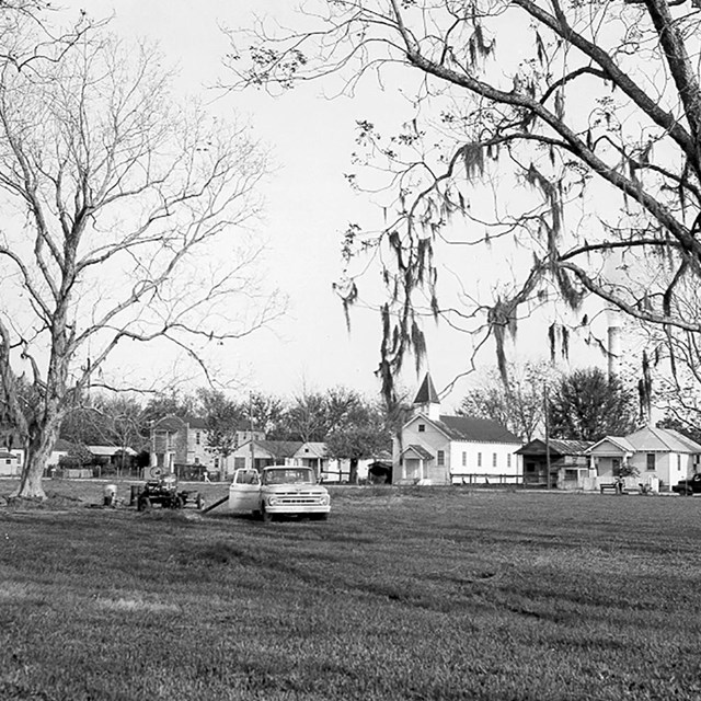 historic photo of neighborhood, old truck out  front, homes and trees