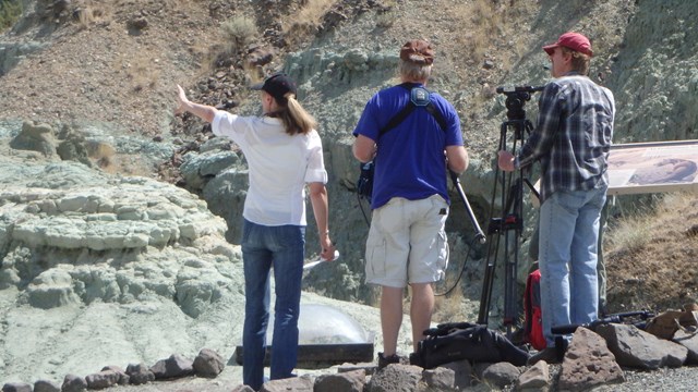 3 filmmakers set up a shot among blue green rocks