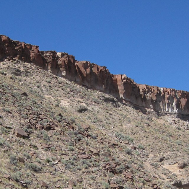A thin layer of tuff rock atop a grassy slope.
