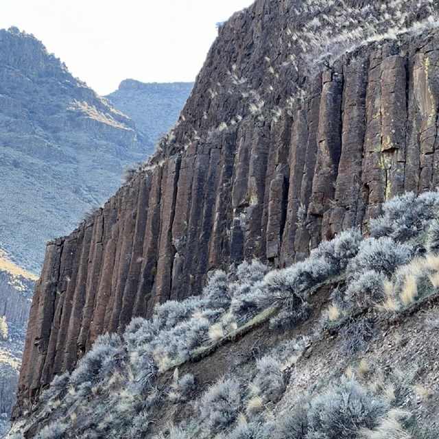 A row of columnar basalts with a grassy slope below