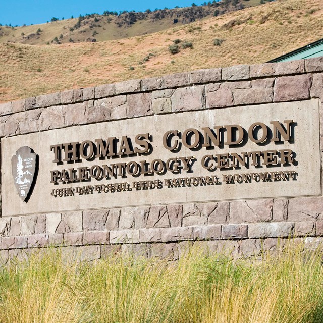 A rock wall outside of a visitor center with metal letters, 