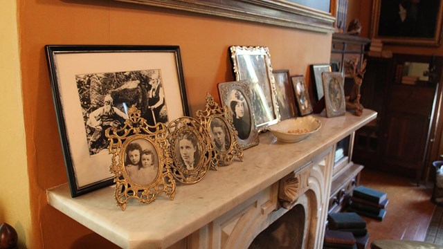 Fireplace mantel with multiple picture frames including photos of family.