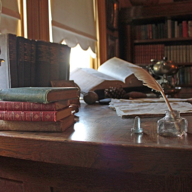A quill and books sit on the corner of John Muir's desk.