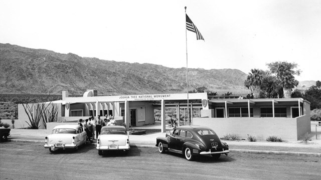 A black and white photo of old cars in front of a building