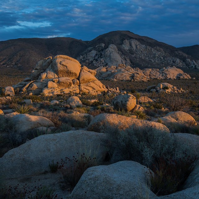 Low light on boulder piles with a dark cloudy background.
