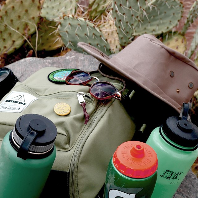 a backpack with water bottles, a hat, and sunglasses