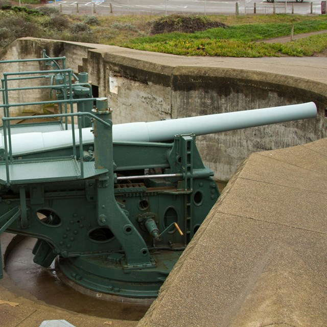 Two people stand at the end of a large canon guarded by a cement wall
