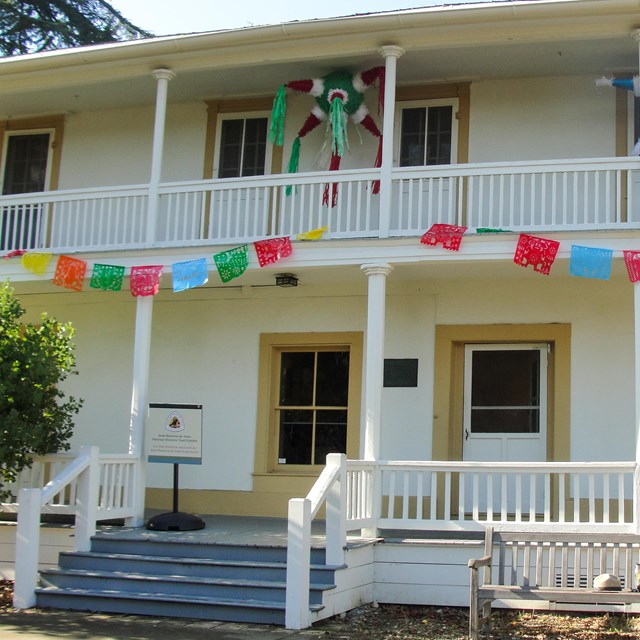 An off-white two-story building with white-railed porches on both levels