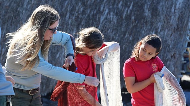 NPS employee teaching net-throwing to children