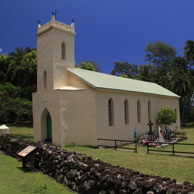 A light-colored large church building with a steeple and large windows. 