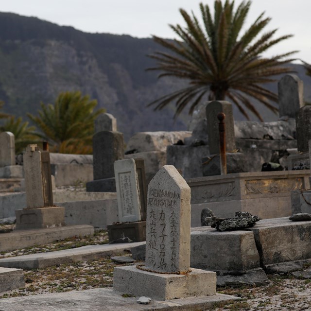 Multiple grave stones with cliffs in the background.