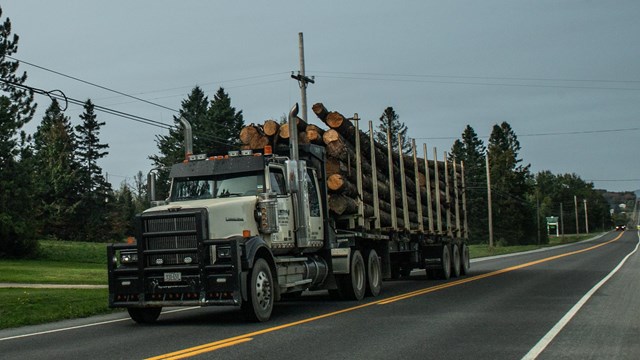 a full logging truck on a two lane highway