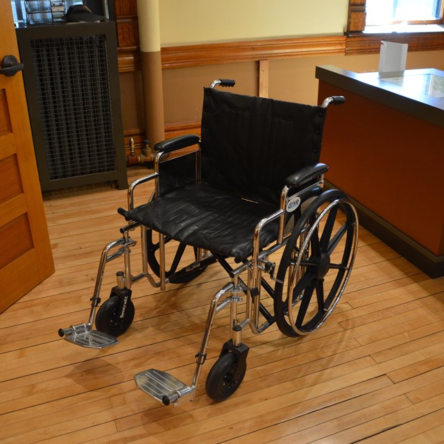 An empty wheelchair next to a desk.