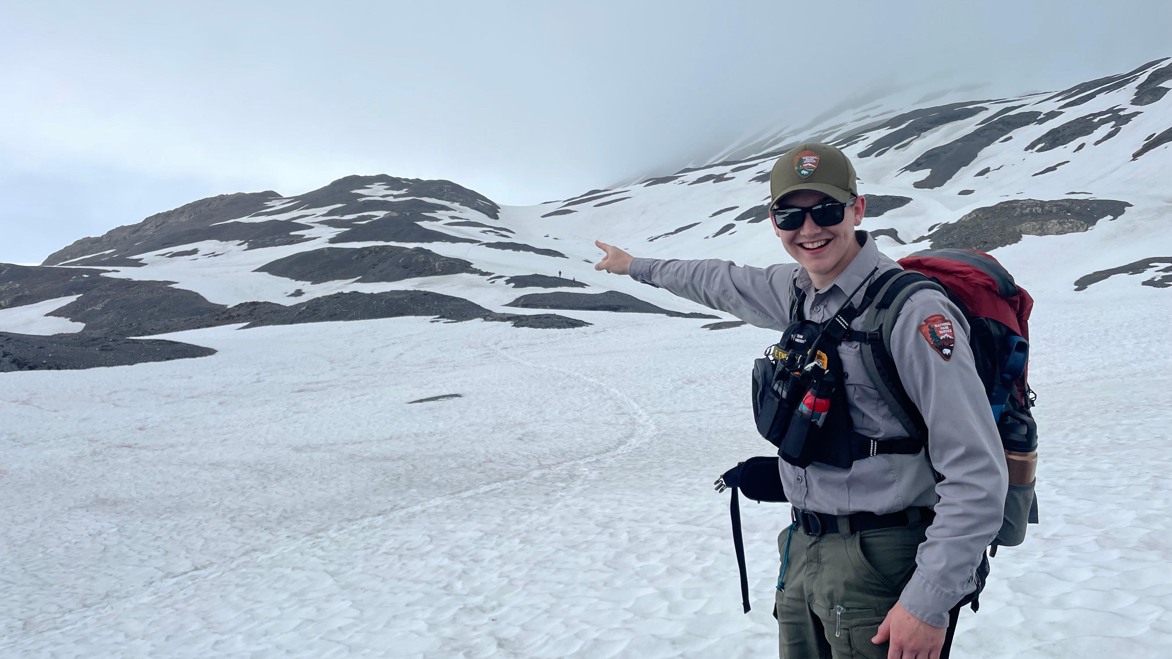 A park ranger points towards snow-covered terrain