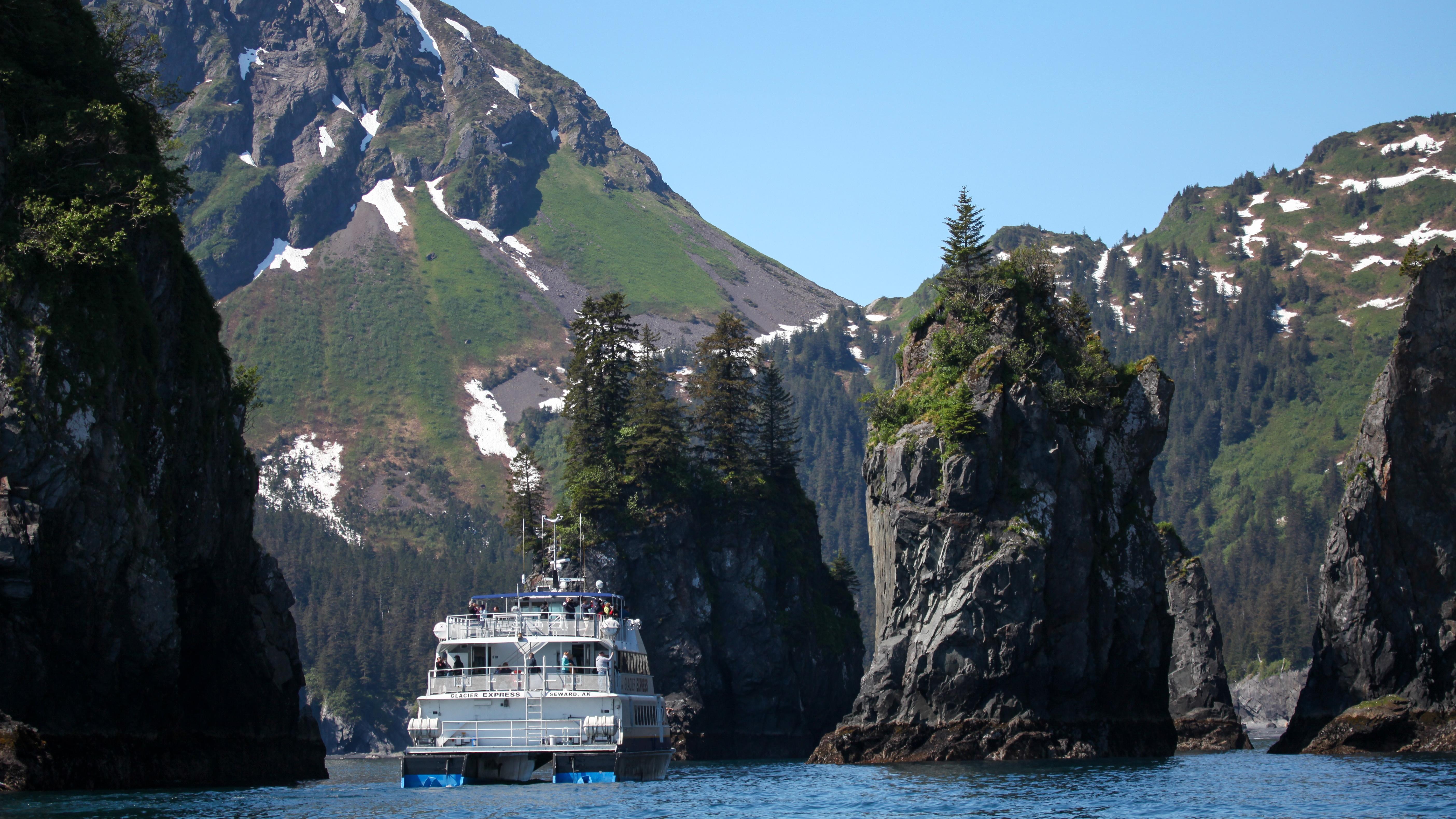 A tour boat next to ocean sea stacks