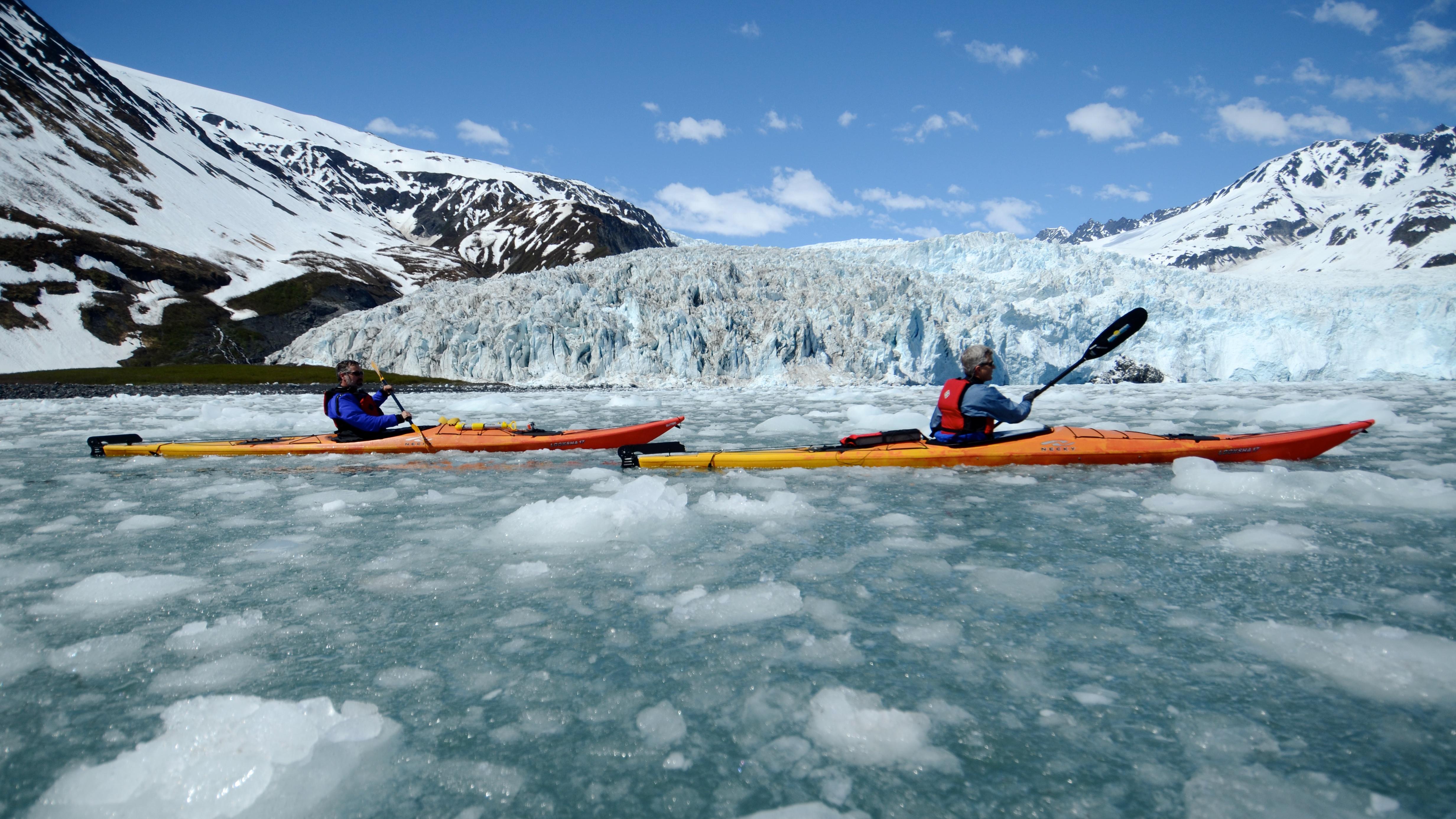 Two kayaks on icy water with a glacier beyond
