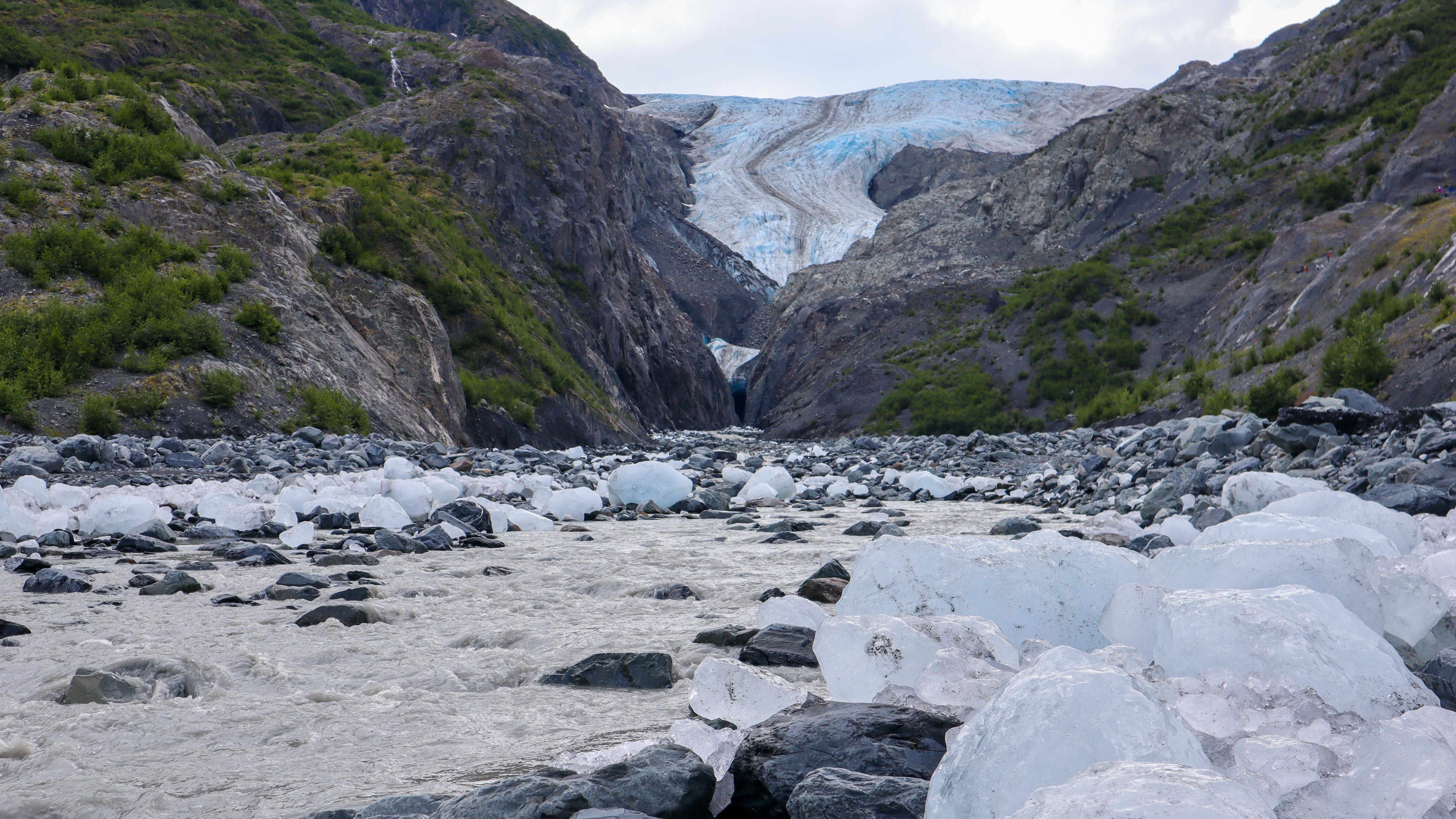 Small pieces of glacial ice along a stream coming from a glacier in the distance