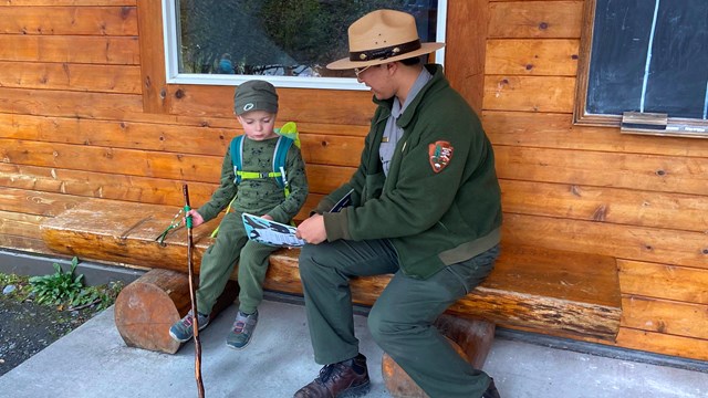 A child works on a junior ranger book with a park ranger