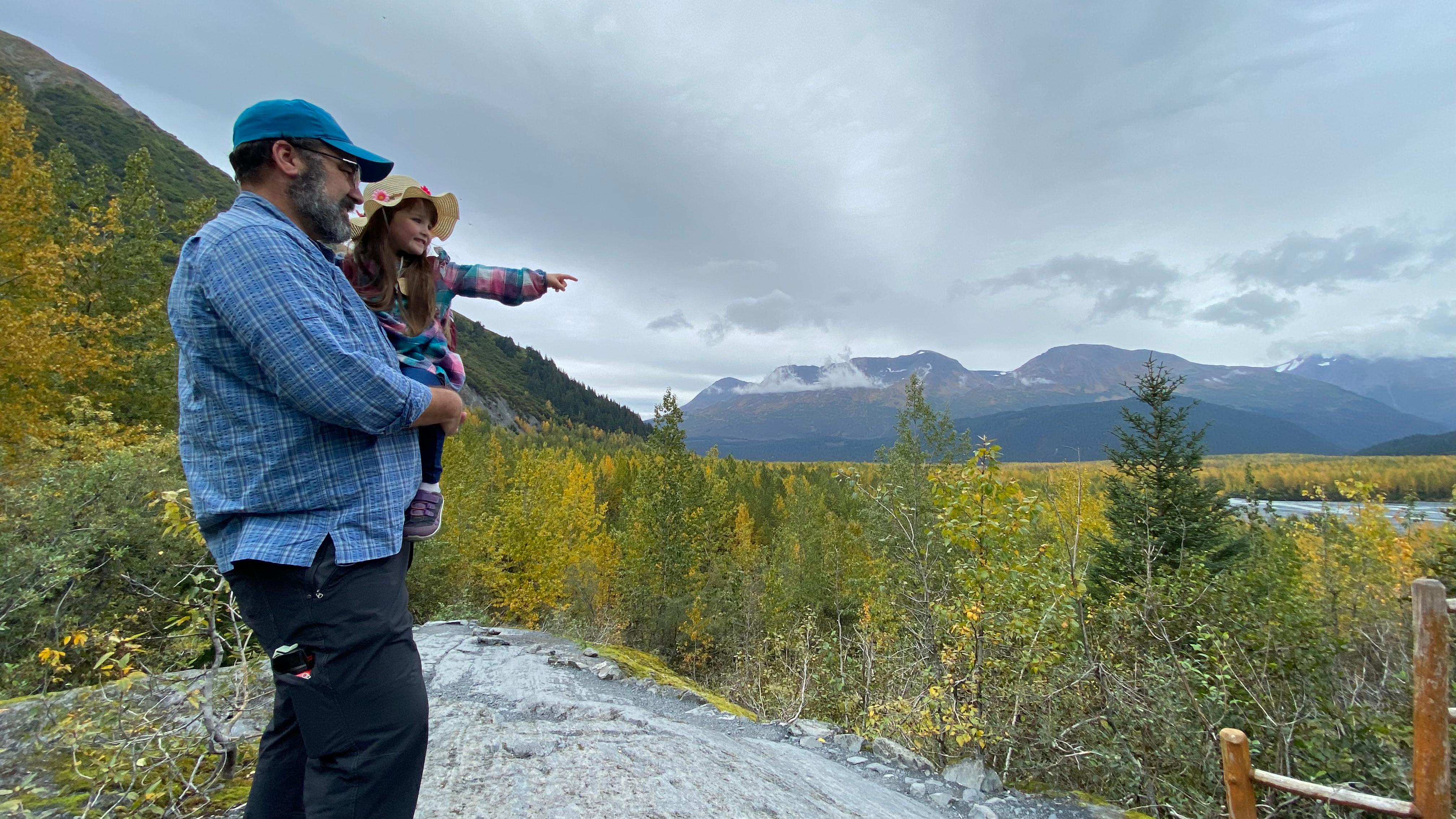 A person holding child pointing towards scenic vista