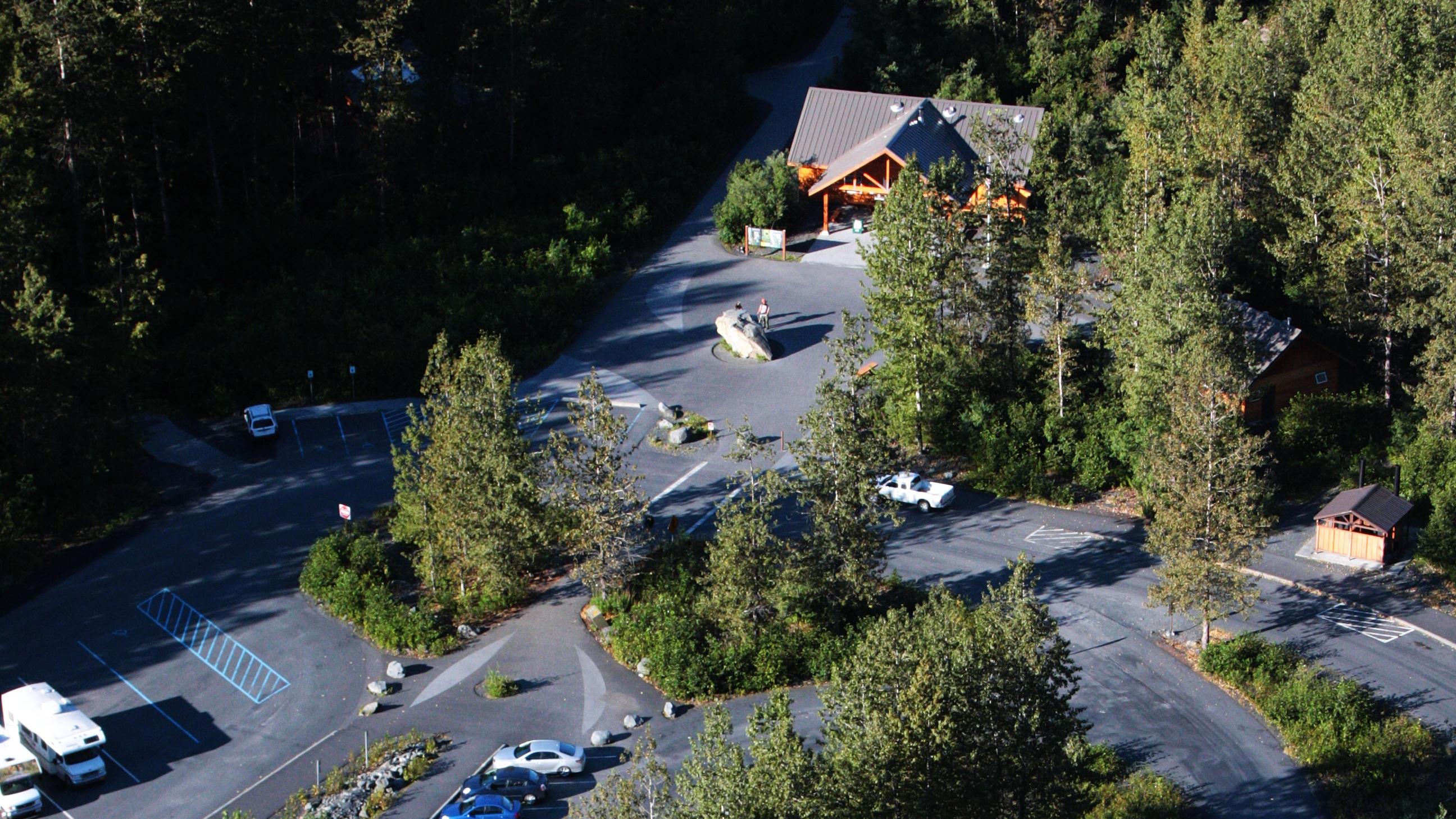 An aerial view of parking lot and visitor center amongst forest