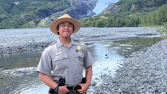 A park ranger stands on the Outwash Plain with Exit Glacier in the background.