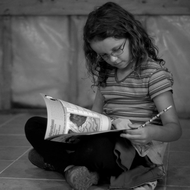 A child sits on the floor looking at a book. 