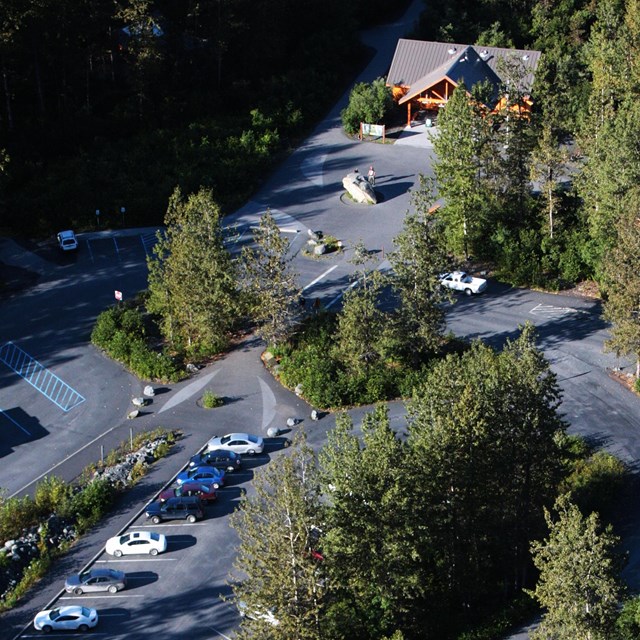 Aerial view of the Exit Glacier Visitor Center and Parking Area with green forest surrounding.