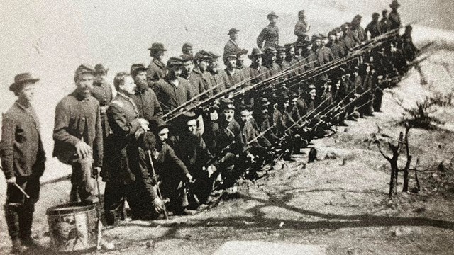Black and white image of Civil War era soldiers formed in two ranks with fixed bayonets.