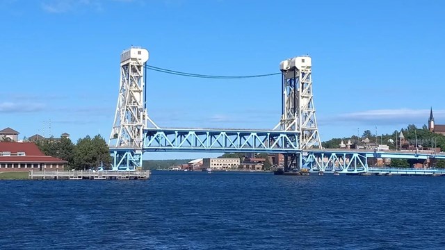 Blue water stretches out spanned by a blue and tan bridge.