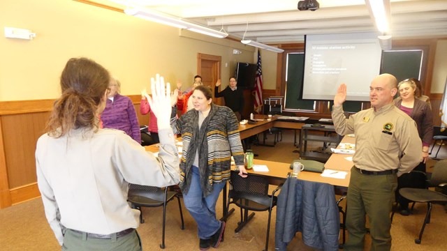 A group of people hold their right hands up and recite an oath.