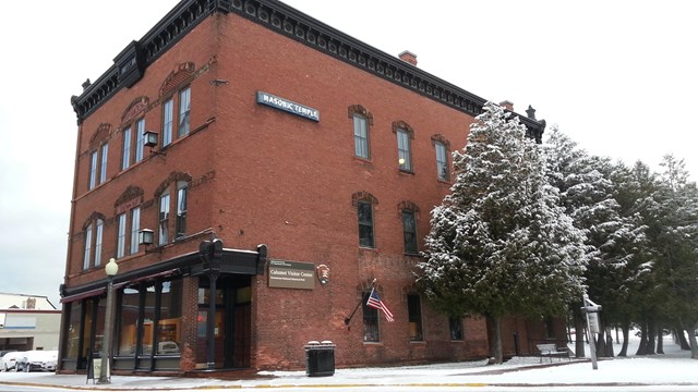 The exterior of the Calumet Visitor Center, a brick building lined with snow-covered trees.