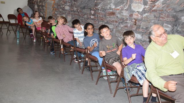 A group of people sit in a row in chairs all leaning to one side simultaneously.