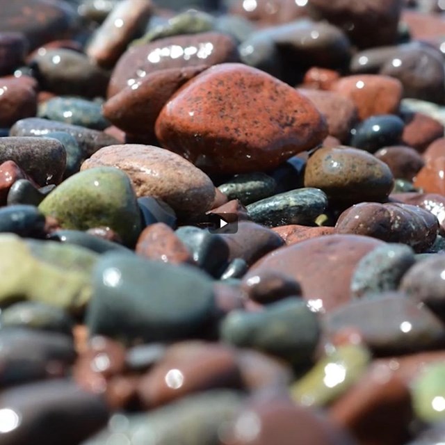 Closeup of multi-colored beach stones glistening from sunshine.
