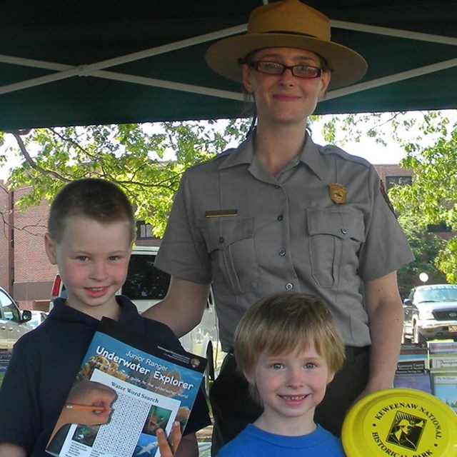 A park ranger poses with two junior rangers