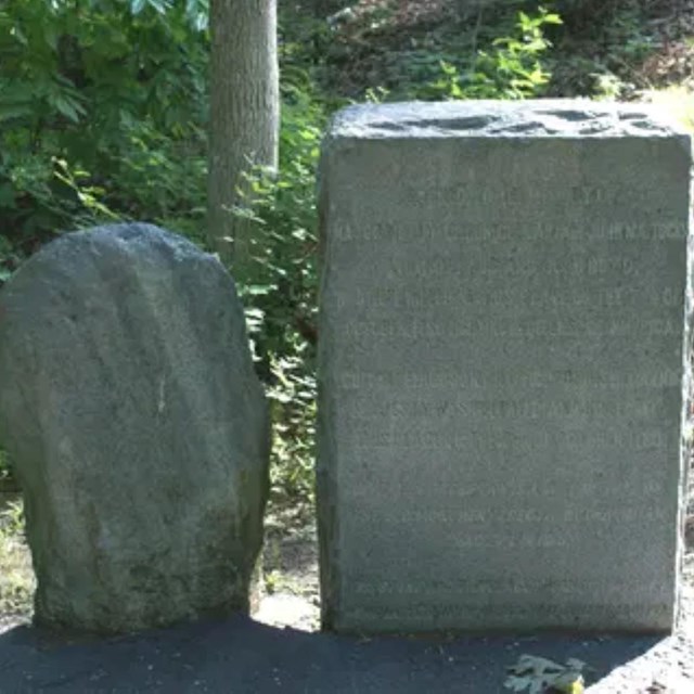 Two stone monuments, one smaller and round and one larger and rectangular. 