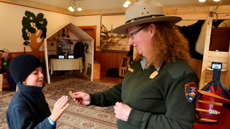 A ranger hands a badge to a boy