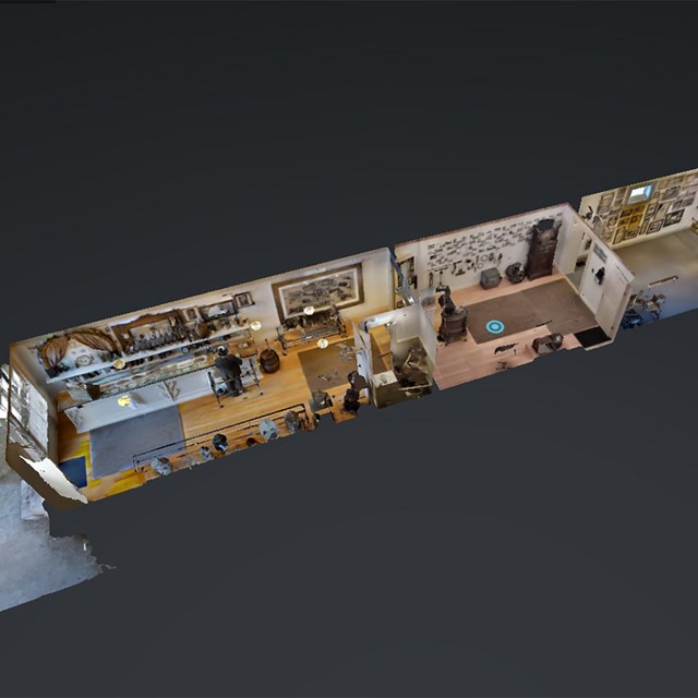 Dollhouse view of a long narrow building with three rooms and lots of furnishings