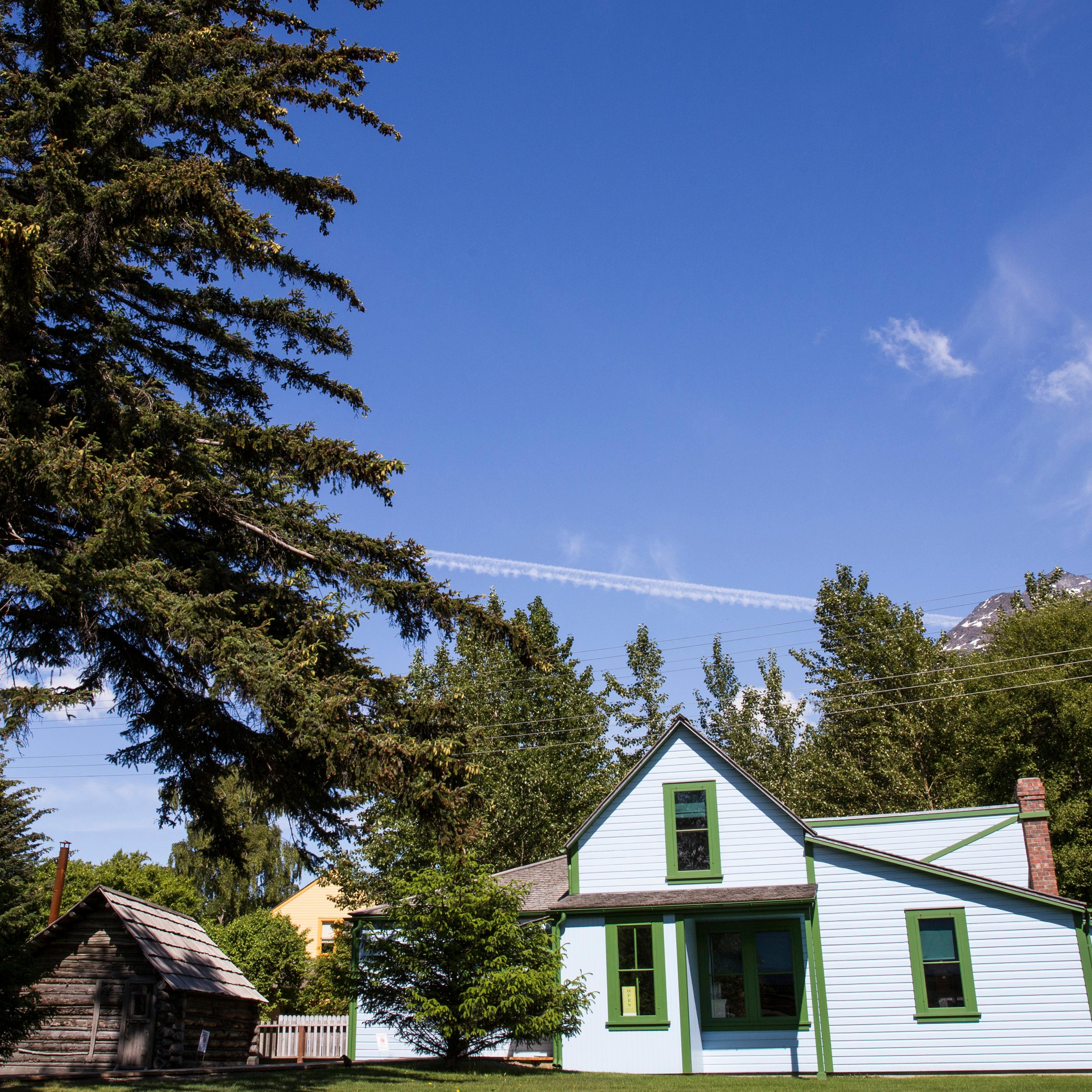 a bright blue building and small log cabin under a blue sky