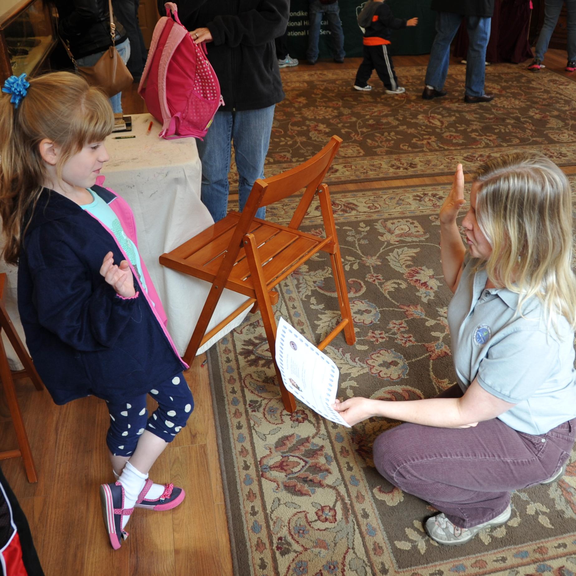A teacher kneels and swears in a Junior Ranger.