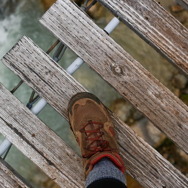 Hiking boot on bridge with river below