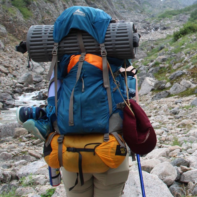 A backpacker hikes on rocky terrain