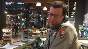 NPS ranger looks directly at viewer while answering phone at a retail desk. 