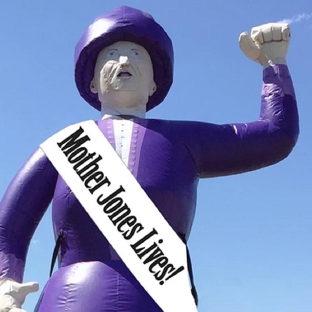 Large inflatable float/balloon of Mother Jones in purple dress with raised fist