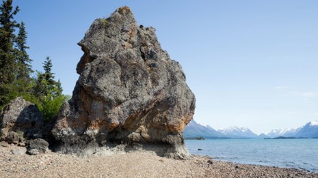 a large boulder sits on a beach