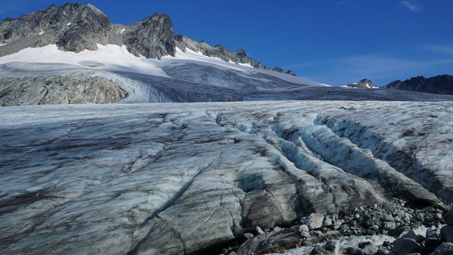 The surface of a glacier with a mountain peak rising in the back