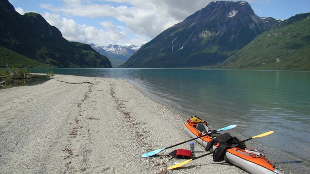 A kayak on a sandy beach next to a lake