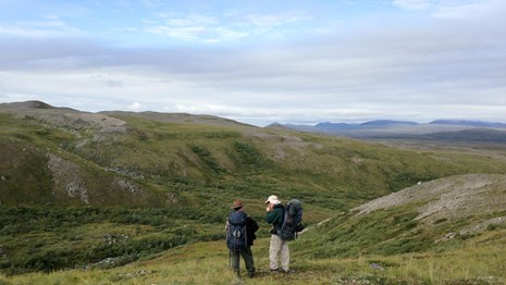 two backpackers stand on a tundra overlook