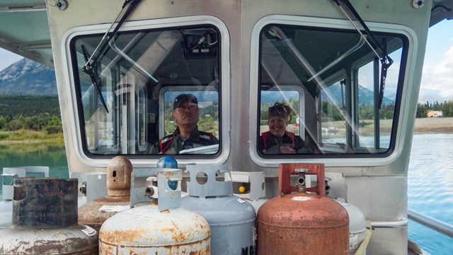 A man and a woman look out of a boat window. 