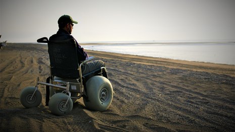 a man sitting in a dune buggy wheelchair on the beach