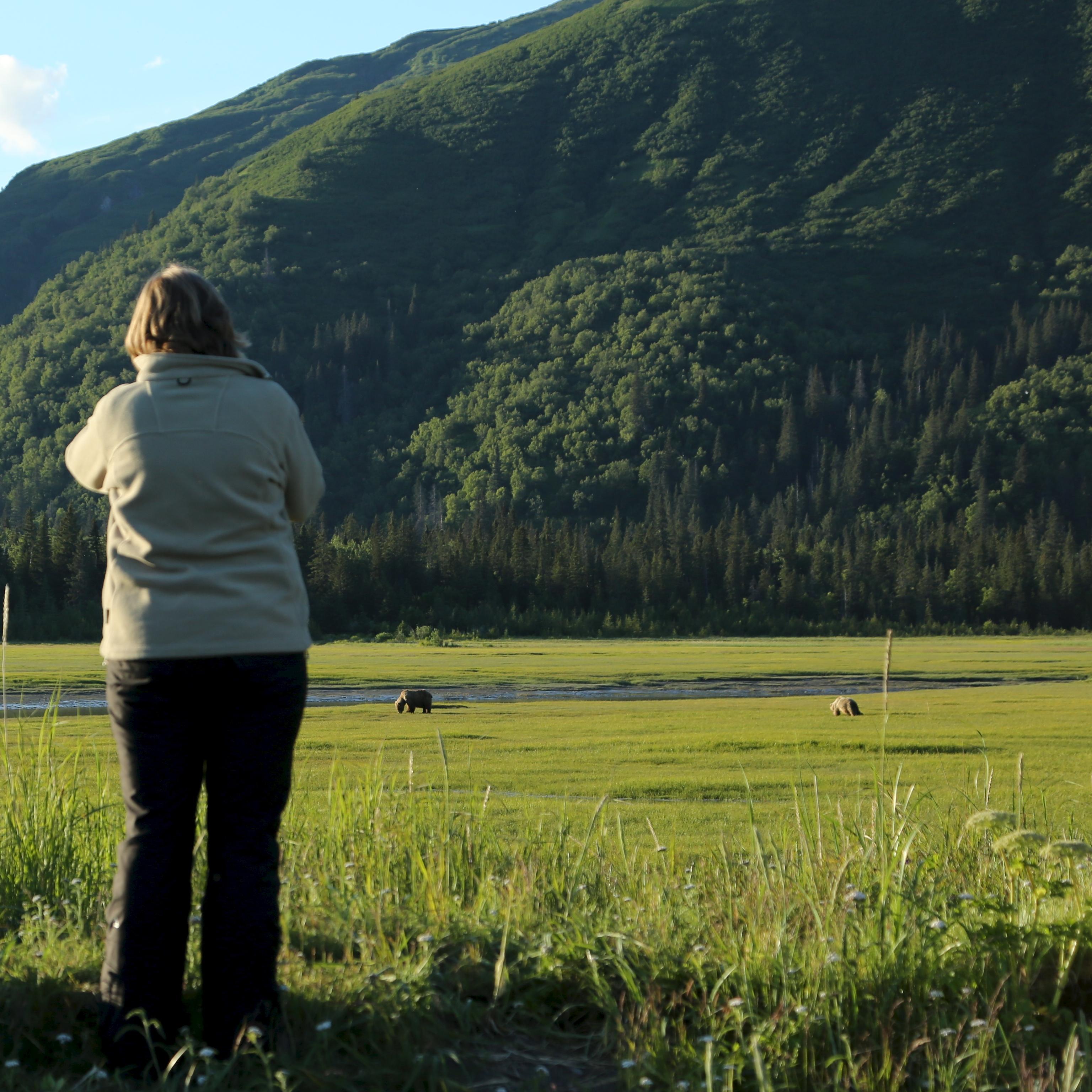 Two women and a man watch bears from a distance